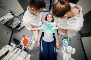 Dentist and dental assistant performing a dental crown procedure on a patient in a modern clinic setting, highlighting the commitment to restorative dentistry at Deer Park Dental Group.